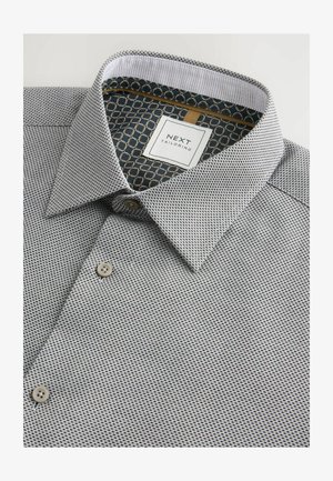 Meeste särk musta ja valge mikro-mustriga, millel on struktureeritud krae, beežid nööbid ja kontrastne geomeetriline sisekrae vooder.