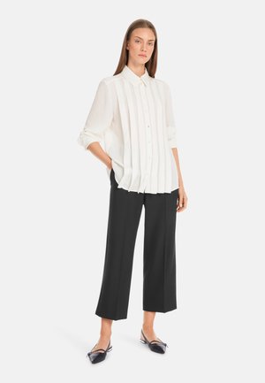 White button-up shirt with vertical pleats, paired with black wide-leg trousers and flat, pointed shoes. Simple design, light texture.