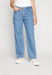 Jasnoniebieskie dżinsowe spodnie z wysokim stanem, zapinane na pięć guzików, z dwiema przednimi kieszeniami; szerokie nogawki; subtelne zagnieceń na materiale.