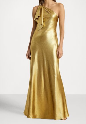 Mujer con un vestido dorado brillante hasta el suelo, de un solo hombro, con un drapeado decorativo en el hombro.