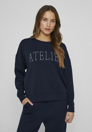 Sudadera azul marina con "ATELIER" bordado en blanco, con un corte relajado, cuello redondo y dobladillo acanalado. Textura de tela suave y lisa.