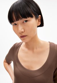 Brown fitted top with a scoop neckline and short sleeves. Smooth texture and simple design, highlighting a minimalistic style.