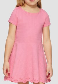 Robe rose à manches courtes en coton texturé avec une jupe évasée et une bordure en broderie œillet au bas. Encolure ronde, design décontracté.