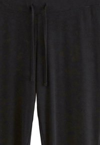Joggers neri a costine con elastico in vita, dotati di un laccio di regolazione e una texture morbida. Comprendono cuciture laterali per un design aggiuntivo.