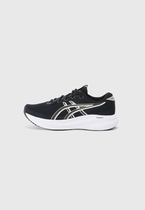Chaussure de sport noire avec dessus en maille, accents argentés et col rembourré. Elle dispose d'une semelle intermédiaire blanche et d'une semelle extérieure noire pour une meilleure traction.