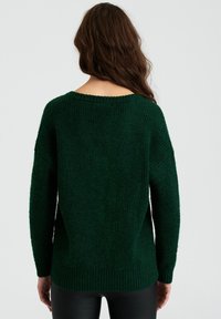 Dunkelgrüner Strickpullover mit lockerem Sitz, weitem Ausschnitt und geripptem Saum. Strukturierter Stoff, lässige Ärmel und seitliche Schlitze.
