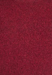 Lähiotoksia punaisesta villakankaasta, jossa on pehmeä, uritettu neulepinta, joka näyttää hienoja kuituja ja luonnollisia langan vaihteluja.