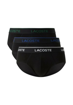Tre slip neri da uomo impilati, ciascuno con una fascia di colore diverso e logo "LACOSTE" in verde, blu e bianco.