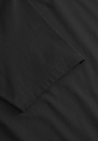 Czarna bawełniana koszulka z okrągłym dekoltem i krótkim rękawem. Gładka faktura z przeszyciami przy rękawach, charakteryzująca się jednolitym kolorem.