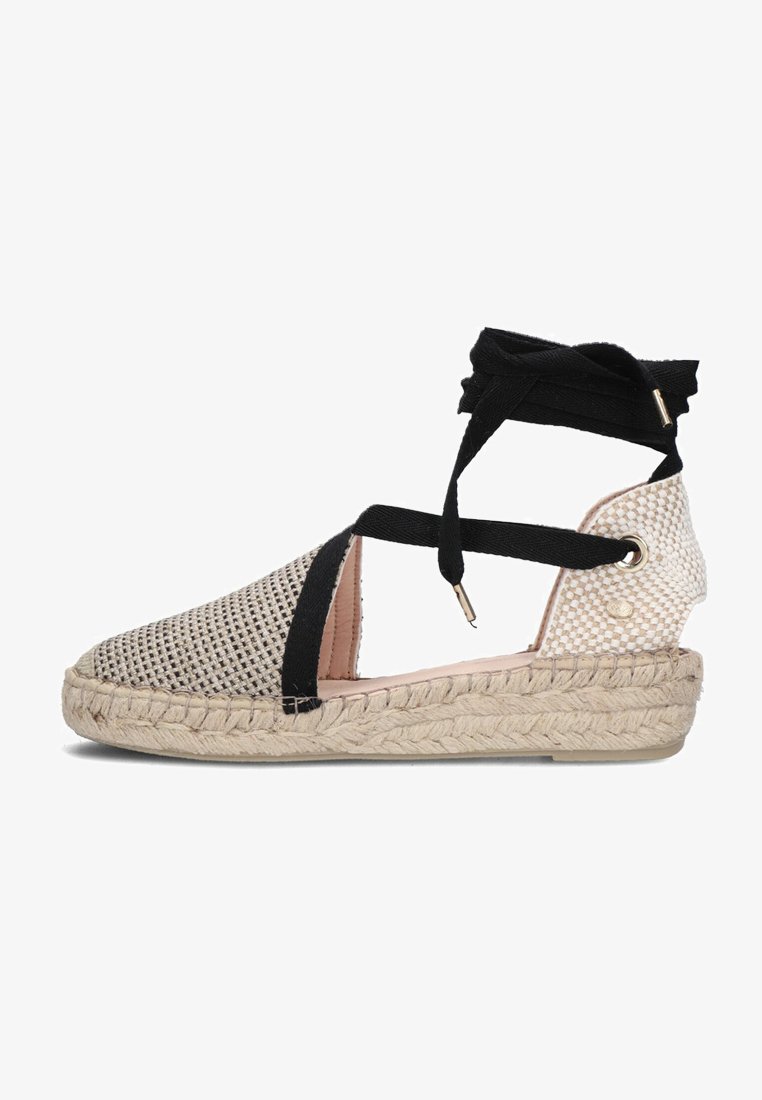 Espadrille met geweven beige canvas en zwarte textielbanden. Beschikt over een gevlochten jute zool en verstelbare enkelbanden. Gladde binnenvoering.