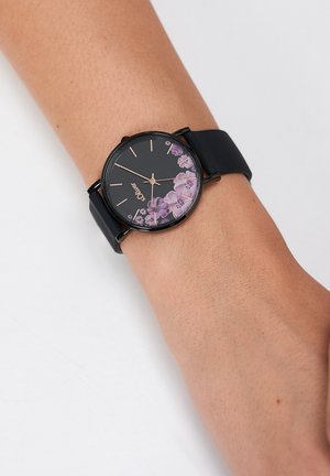 Black wristwatch with floral design on the dial, featuring a silicone band and rose gold hour markers.