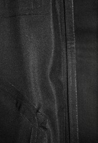 Svart tyg med en lätt lyster, med en slät textur och en synlig söm. Inga andra mönster eller anmärkningsvärda detaljer.