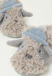Gray fabric slippers shaped like a dog, with a fluffy texture, woolen ears, and a light blue hat featuring a pom-pom detail.