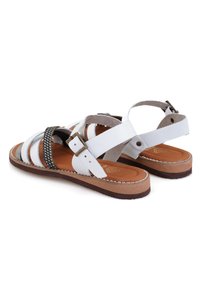 Weiße Ledersandalen mit schwarzen geflochtenen Riemen, verstellbaren Schnallen am Knöchel sowie hellbraunen gepolsterten Fußbetten und Außensohlen.