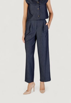 Denimová látka, námořnický modrý crop top s knoflíky a široké kalhoty v námořnické modři. Hladká textura, s vysokými nude botami jako akcenty.