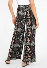 Pantalons larges en tissu noir avec un motif floral et paisley en menthe, pêches et marron. Ceinture élastique avec une coupe décontractée.