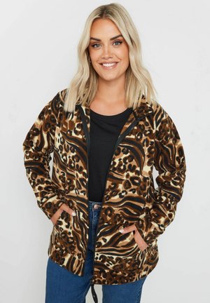 Brown and black animal print zip-up fleece jacket with front pockets, a hood, and a relaxed fit, paired with a black top and denim jeans.
