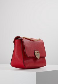 Borsa a tracolla in pelle rossa con finitura testurizzata, hardware a forma di cuore in oro, tracolla a catena e chiusura a pattina, con marchio "Valentino".