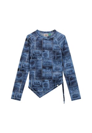 T-shirt à manches longues en denim bleu avec un collage de publicités de stations-service. Il présente un ourlet asymétrique unique et une finition texturée.
