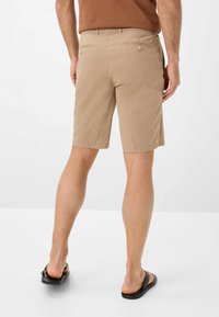Beige bomulds shorts med to baglommer, subtil tekstur og lige pasform. Parret med sorte flip-flops. Minimalistisk design.