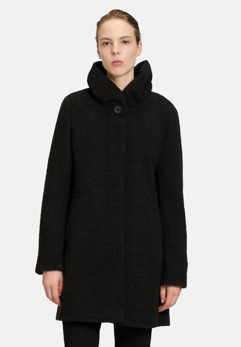 Zwarte wollen jas met een hoge kraag, simpel ontwerp, sluiting met één knoop en textuurstof. Geen zichtbare patronen of accenten.