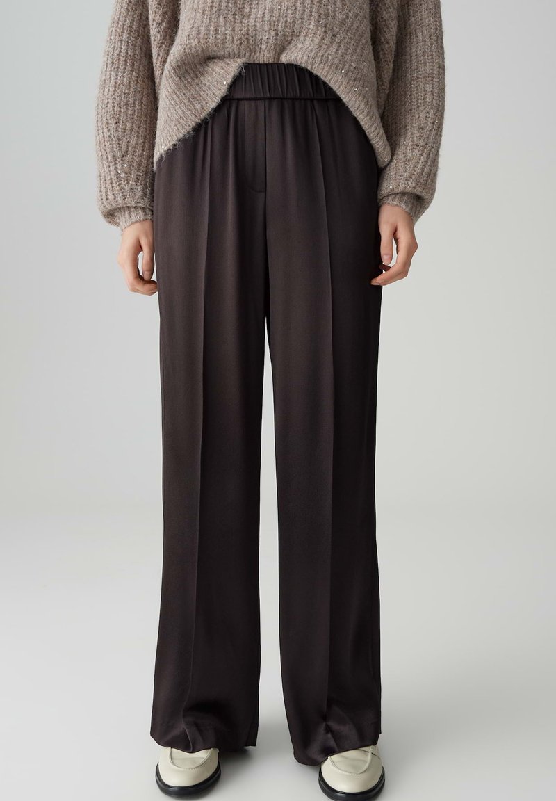 Pantaloni neri a gamba larga con vita elastica, realizzati in un tessuto morbido, caratterizzati da un design pulito e una leggera lucentezza.