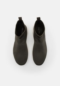 Czarne dziane botki za kostkę z teksturowaną cholewką, z pętelką do łatwego zakładania i białą gumową podeszwą.