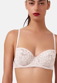 Blonde bralette i blød pink med formede kopper, justerbare stropper, bølgede kanter, blomstermønster og underwire støtte.