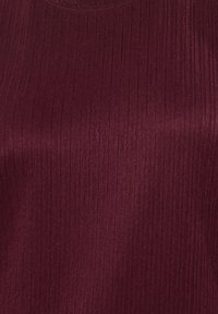 Burgundowa top z teksturowanym wzorem, z okrągłym dekoltem i gładkim wykończeniem. Materiał wydaje się lekki i elastyczny.