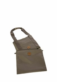 Sac en tissu marron avec une finition texturée, de forme rectangulaire, doté de deux poignées et de deux accents en cuir à l'avant. Fermeture zippée.