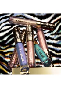 Six tubes de gloss à lèvres Just Cavalli x KIKO Milano dans différentes nuances métalliques avec des capuchons à motif zèbre sur un fond rayé zèbre.