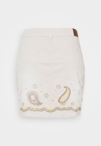 Béžová denim mini sukně s paisley vyšíváním ve zlaté a hnědé barvě, s květinovými detaily a dekorativním stehem podél lemu.
