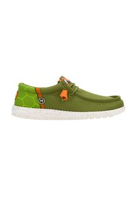 Groene canvas schoenen met een oranje accent, voorzien van een hexagonaal patroon aan de zijkant en een textuur witte zool met spikkels.