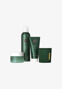 Gommage corporel Green Ritual of Jing, gel douche moussant, crème corporelle apaisante et bougie striée avec étiquette dorée sur fond blanc.
