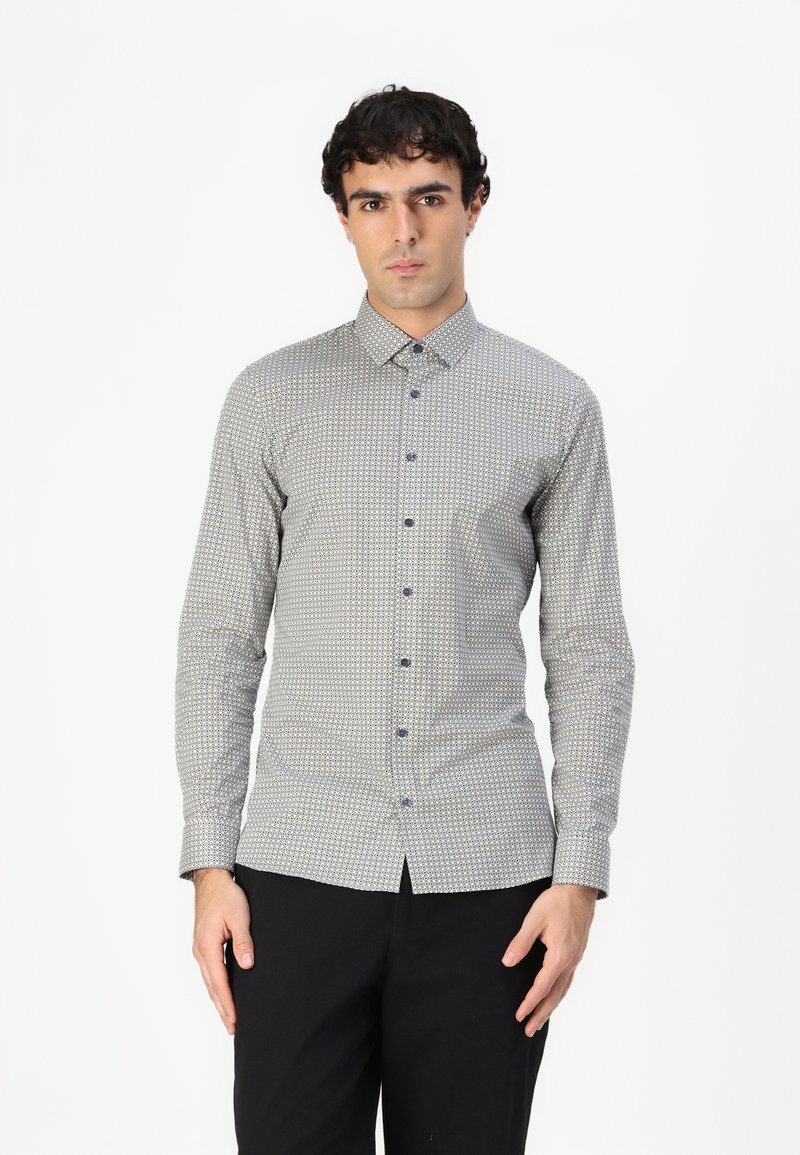 Camicia button-up in un tessuto grigio chiaro con un motivo geometrico in blu navy e azzurro, dotata di colletto alla francese e maniche lunghe.