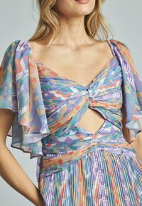Faltendes Kleid aus leichtem, mehrfarbigem Stoff mit geometrischen Mustern, flatternden Ärmeln und einem Schlüsselloch-Ausschnitt an der Brust.