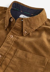 Chemise en velours côtelé marron à boutons, avec col, poche poitrine et doublure intérieure du col bleu marine à bordure rayée.