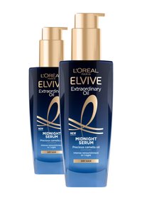Le bottiglie di L'Oréal Elvive Extraordinary Oil, di colore blu trasparente con dettagli dorati, presentano tappi a pompa. L'etichetta include "Siero di Mezzanotte" per capelli secchi.