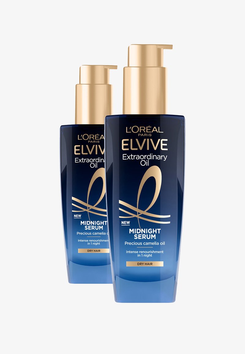 Le bottiglie di L'Oréal Elvive Extraordinary Oil, di colore blu trasparente con dettagli dorati, presentano tappi a pompa. L'etichetta include "Siero di Mezzanotte" per capelli secchi.
