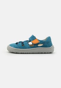 Sinine sametist sandaal halli kummipohjaga, millel on väljakaevamised, Velcro rihm ja oranž aksent külgedel.