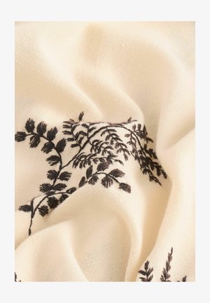 Kremowa tkanina z misternym czarnym haftem kwiatowym, prezentująca szczegółowe wzory liści oraz miękkie, teksurowane marszczenie.