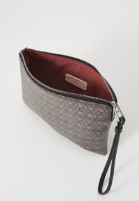 Bolso de mano de cuero gris con un patrón texturizado, forrado en tela burdeos, que cuenta con un cierre de cremallera y una correa para la muñeca.