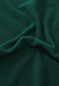 Tissu en polaire vert foncé, texture douce, avec des plis et des rides visibles, créant profondeur et dimension dans l'apparence.