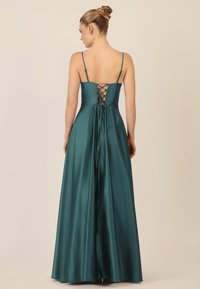 Teal satiini mekko, jossa on säädettävät ohuet olkaimet, nauhakuvaus takana ja täysi hame, joka laskeutuu lattiaan. Sileä pinta, tyylikäs muotoilu.