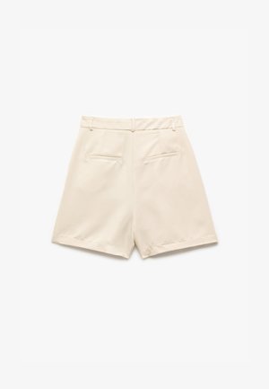 Kermaväriset shortsit, joissa on sileä rakenne, korkea vyötärö, takataskut ja viimeistelty muotoilu. Reunat on huoliteltu ja ommeltu vähäisellä tikkaus yksityiskohdalla.