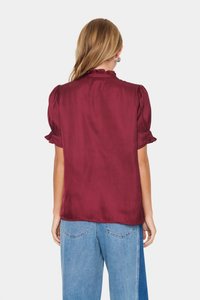 Burgundy selyem blúz puffos ujjal és fodros nyakkivágással. Könnyű, sima tapintású, laza szabás, kék farmernadrággal kombinálva.