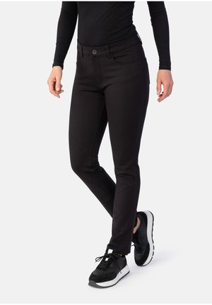 Schwarze Skinny-Jeans aus dehnbarem Material, mit einem mittelhohen Bund, vorderen Taschen und einem Knopfverschluss. Tragen mit schwarzen Schuhen.