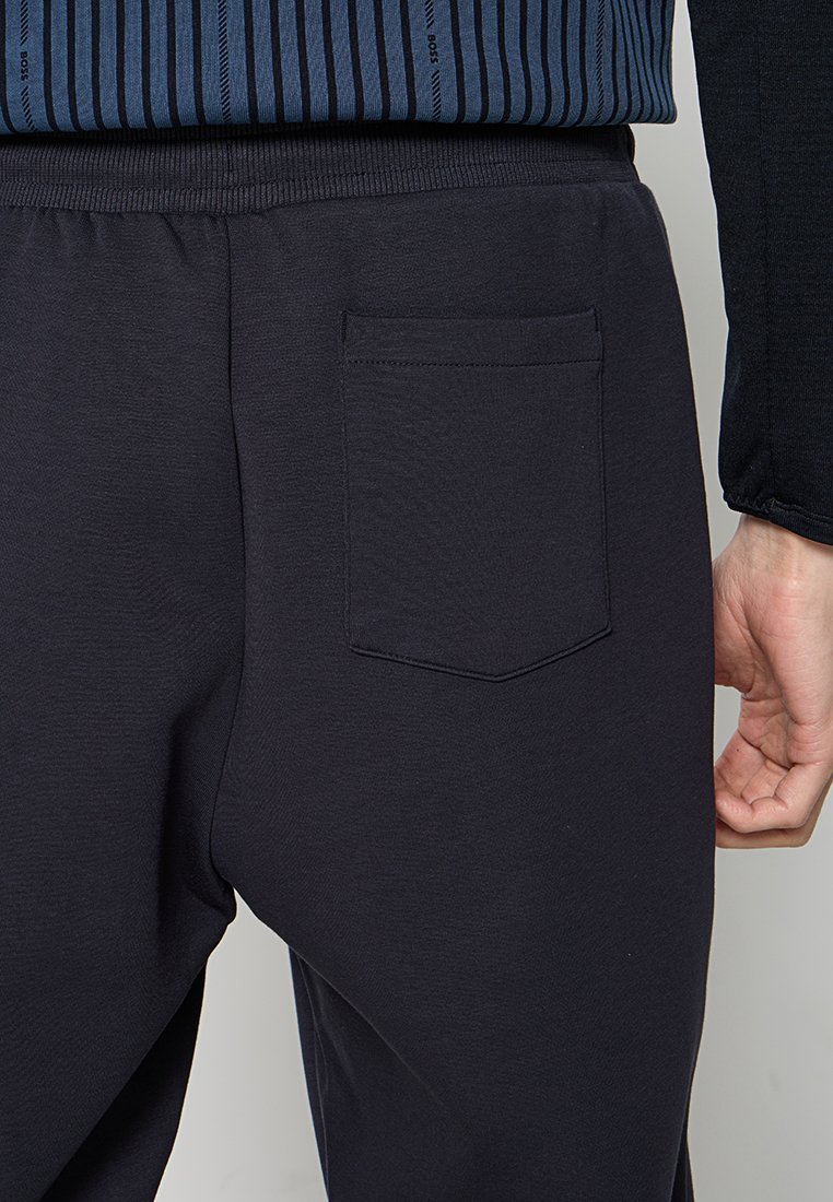 Zwarte joggingbroek met elastische tailleband, voorzien van een enkele achterzak. Gladde textuur, minimalistisch ontwerp, geen zichtbare branding.