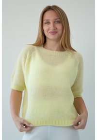 Jasnożółty sweter na druty z krótkimi, prążkowanymi rękawami i luźnym krojem. Materiał jest miękki, lekko przezroczysty i teksturowany.