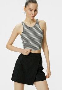 Mustat farkkushortsit, joissa on pehmeä kangas ja sivutaskut, yhdistettynä tiukkaan valko-mustaraidan cropshirtiin.